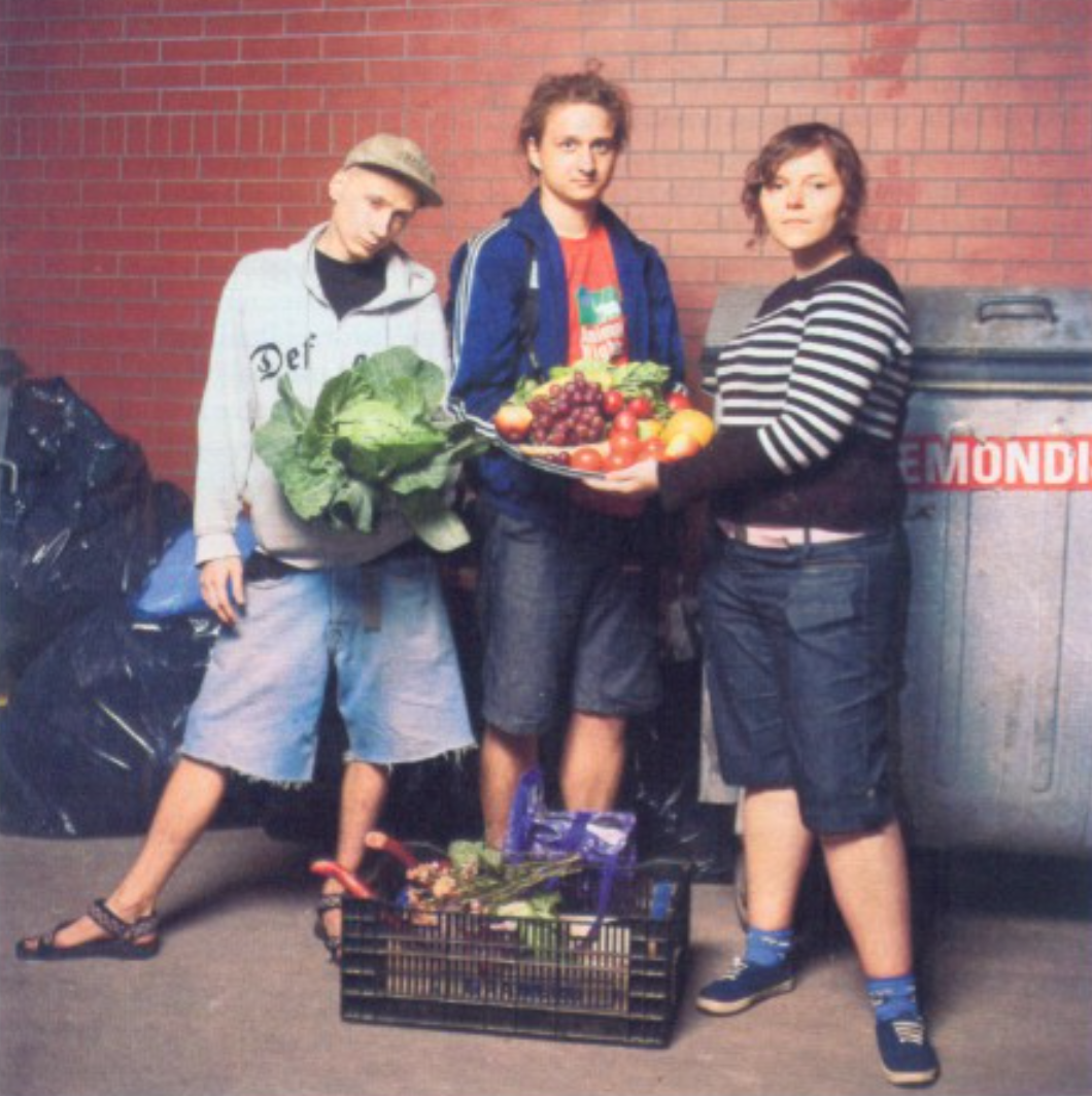 A screenshot of a Newsweek article in Polish. The title says 'Życie za darmo'. There's a somewhat funny photo of three people in jeans short holding up produce on a plate made of a trash can lid.